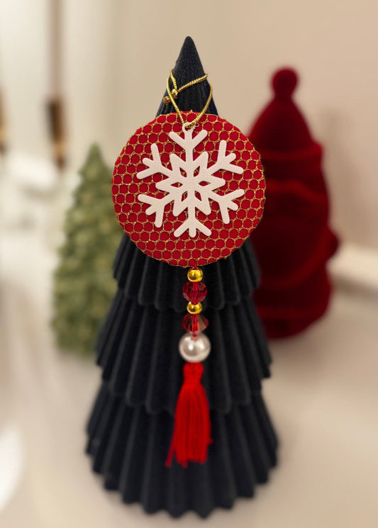Decorative black tree with red snowflake ornament on a neutral background