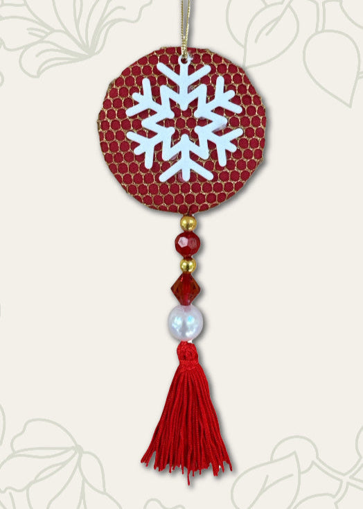 Decorative ornament with a snowflake design on a red circular background, featuring beads and a tassel.