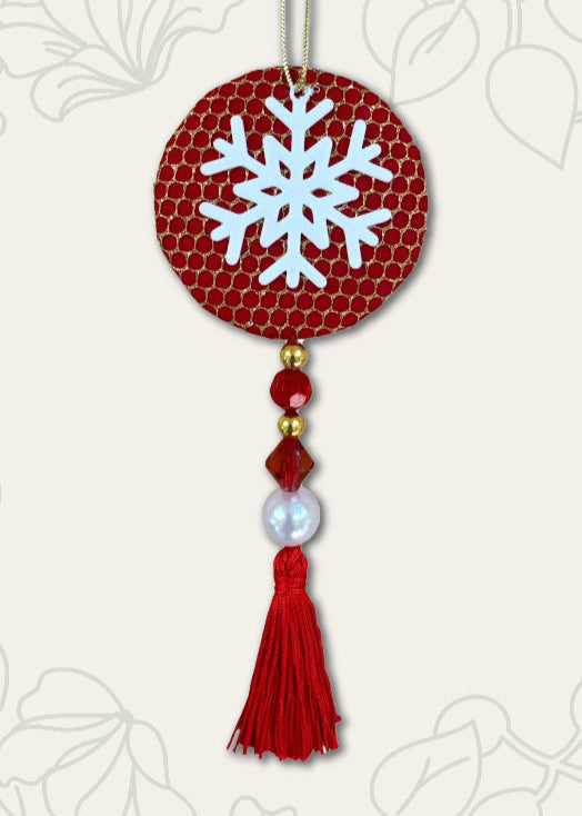 Decorative ornament with a snowflake design on a red background, featuring beads and a tassel.