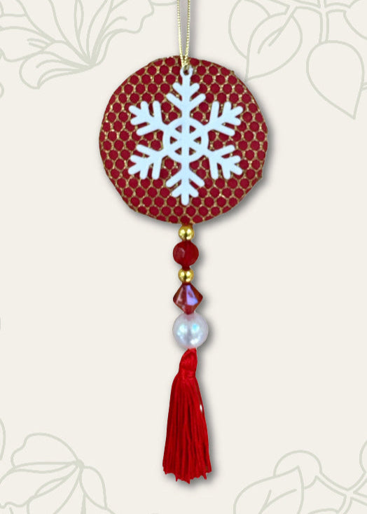 Decorative ornament with snowflake design on a red background, featuring beads and a tassel.