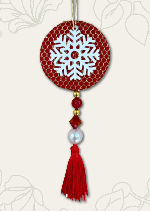 Decorative ornament with snowflake design on a red background, featuring tassels and beads.