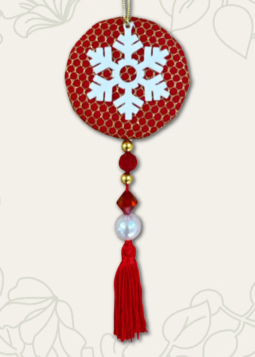 Decorative ornament with snowflake design on a red background, featuring tassels and beads.