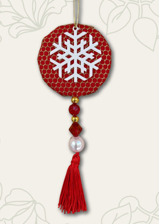 Decorative ornament with red circle, snowflake design, beads, and tassel on a light background.
