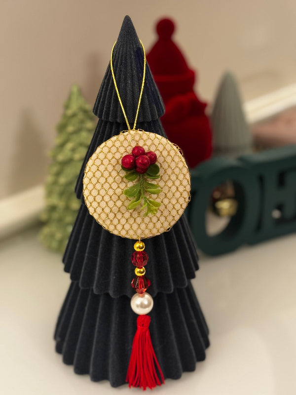 Decorative Christmas tree ornament with a circular gold piece featuring berries and a tassel.